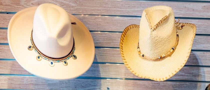 A cream felt hat with a turquoise band and a woven straw cowboy hat on the wall