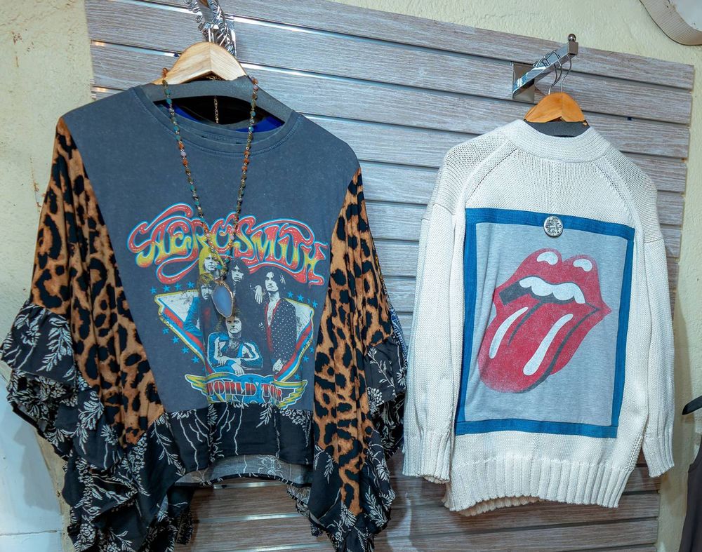 A reworked band tee with leopard-print sleeves and ruffles next to a cream sweater with a band graphic on the back