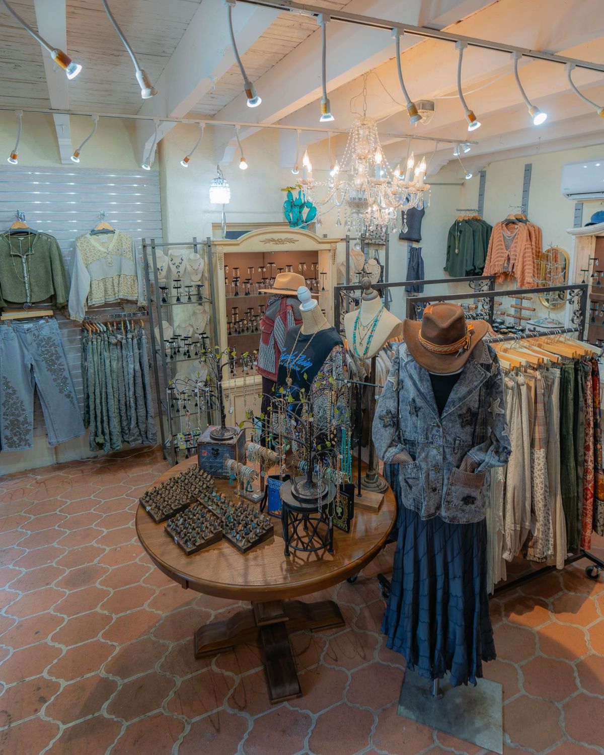 Inside the shop: a round wooden table of rings, mannequins in denim and lace, and a crystal chandelier