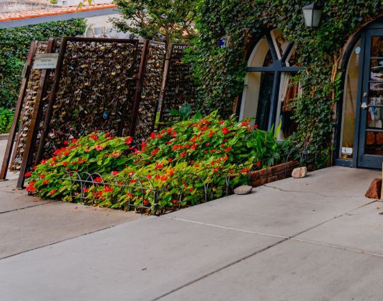 The love-lock gate beside the shop's arched window and flower bed